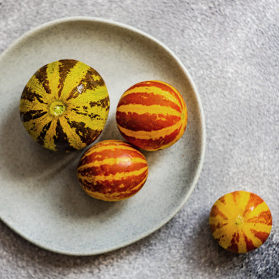 Eine Nahaufnahme der seltenen, exotischen, gestreiften, handgroßen Melonen.